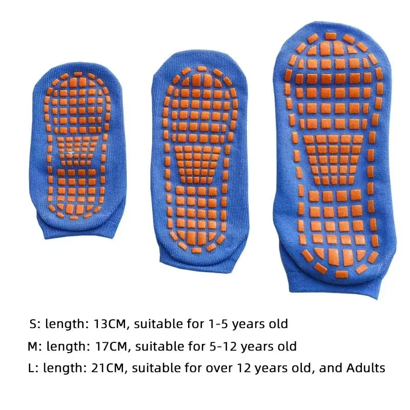 Adult feet in black unisex anti-slip trampoline socks on a gym floor.
