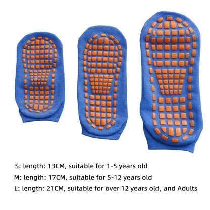 Adult feet in black unisex anti-slip trampoline socks on a gym floor.