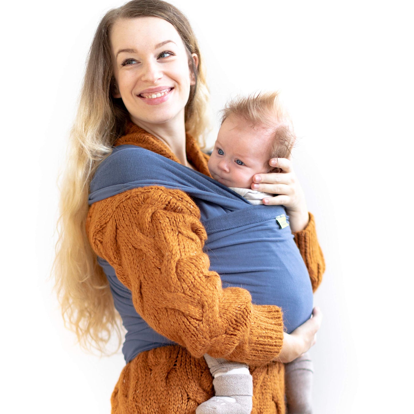 Newborn's feet peeking from a blue baby wrap carrier, showing secure and cozy babywearing.