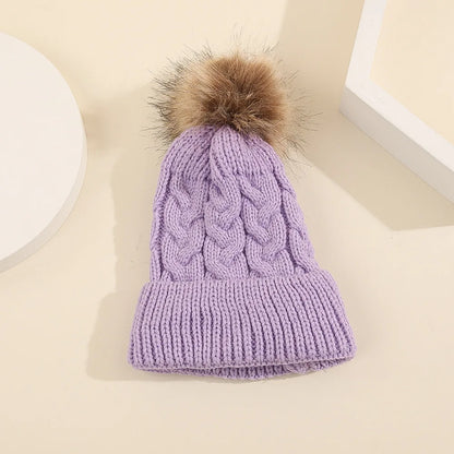 Stack of colorful personalized knit baby hats with pom poms, custom infant apparel
