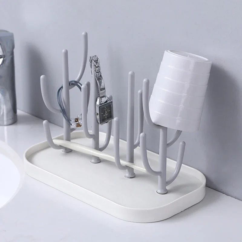 Pink baby bottle drying rack, compact with multiple pegs for bottles & accessories, next to a window.