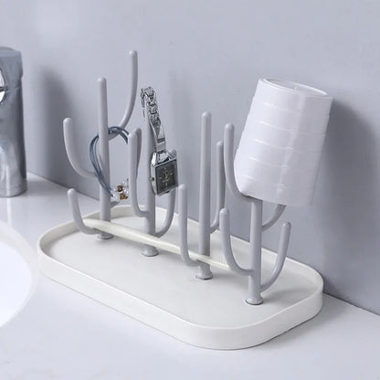 Pink baby bottle drying rack, compact with multiple pegs for bottles & accessories, next to a window.