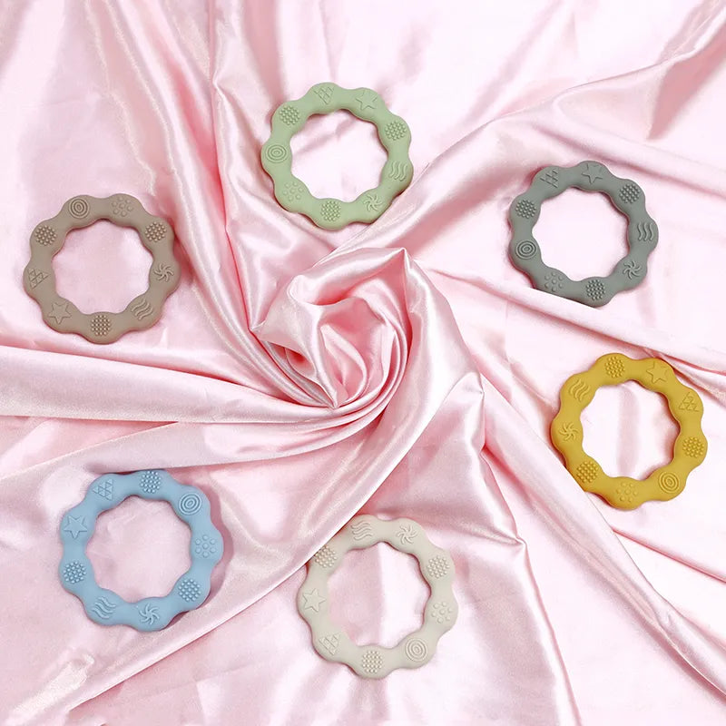 Baby's hand holding a soft pink silicone teether, a BPA-free molar toy for teething relief