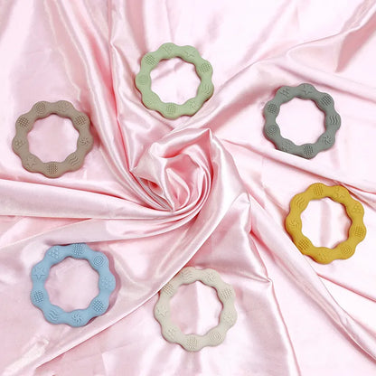 Baby's hand holding a soft pink silicone teether, a BPA-free molar toy for teething relief