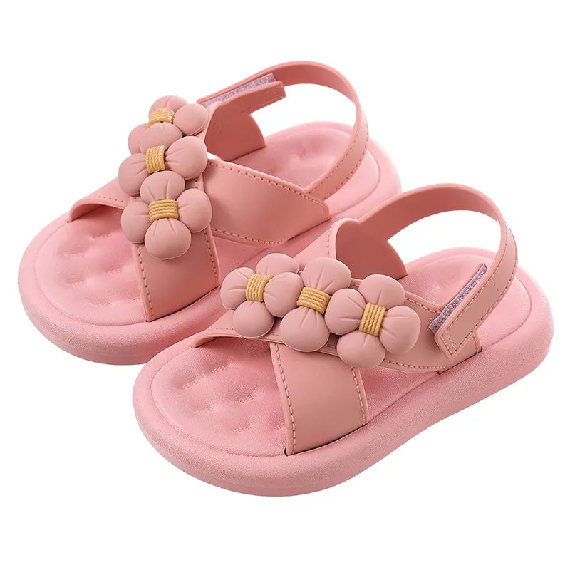 Close-up of pink girls' platform sandals adorned with a delicate flower, stylish kids' footwear.