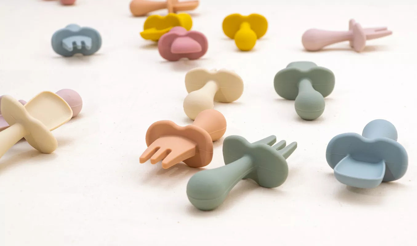 Close-up of green baby silicone fork with rounded tines, toddler self-feeding utensil