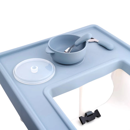 Green silicone placemat on a high chair tray, showing its secure grip. Toddler mealtime accessory.