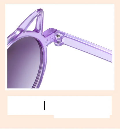 Child smiling while wearing trendy cat-eye sunglasses, ensuring UV protection for delicate eyes.