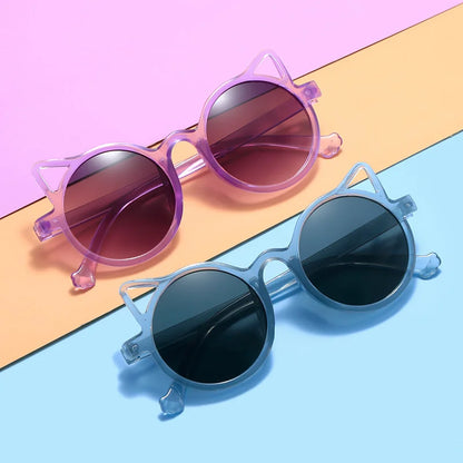 Young girl happily wearing stylish cat-eye toddler sunglasses outdoors.