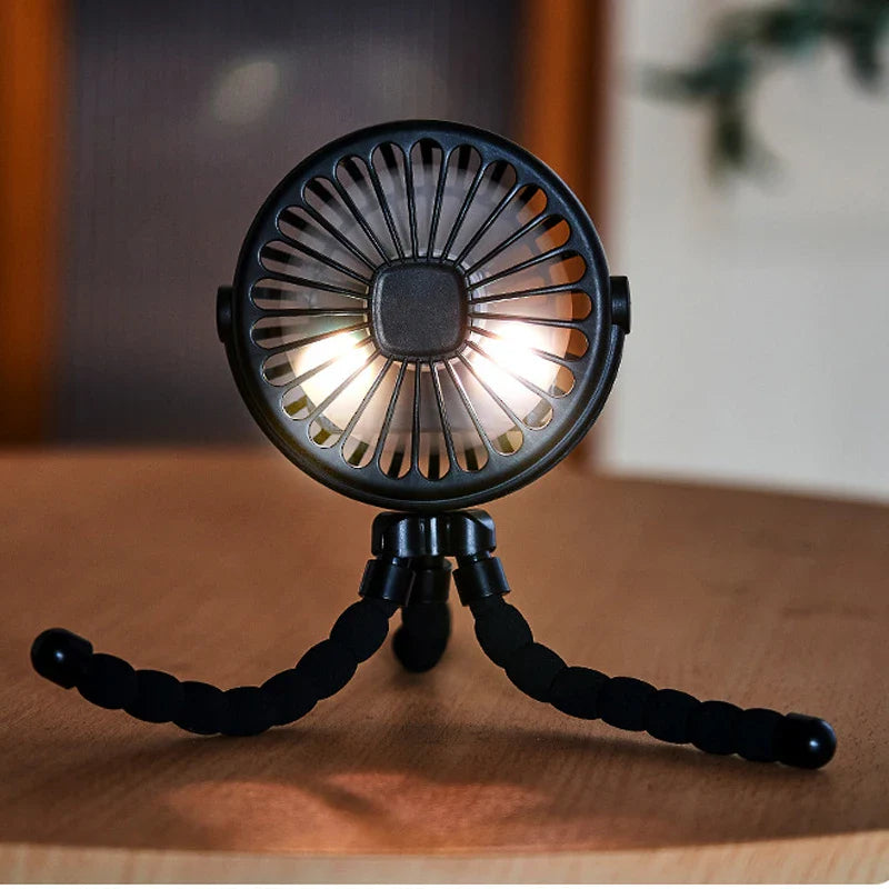 Hand holding a small portable fan, demonstrating its clip-on feature and compact size.