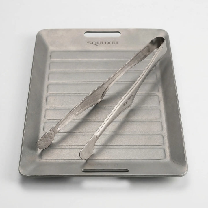 Compact portable ridged grill plate & tongs, designed for solo outdoor cooking & adventure meals while hiking.