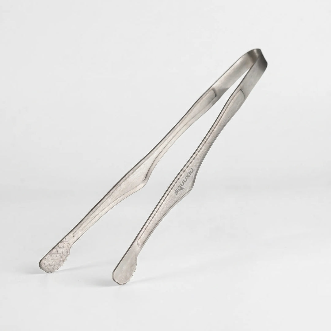 Solo camping grill plate & tongs, showing its non-stick ridged surface, ready for outdoor cooking on a camp stove.