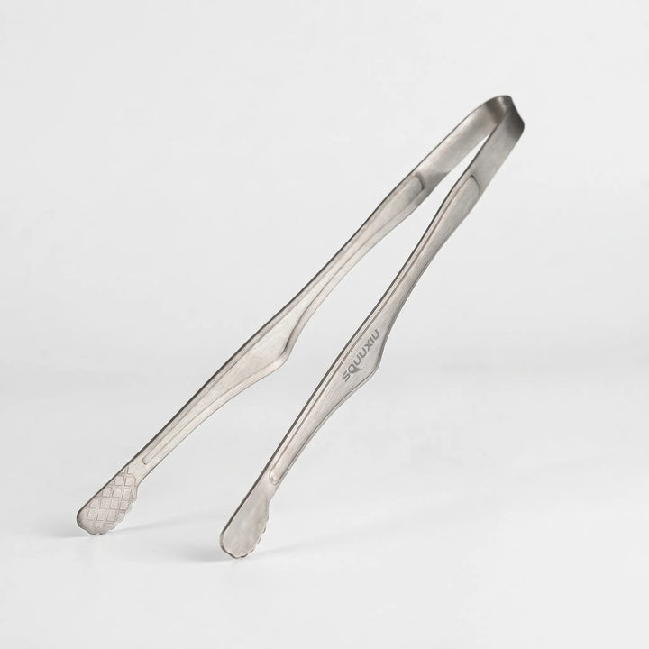 Solo camping grill plate & tongs, showing its non-stick ridged surface, ready for outdoor cooking on a camp stove.