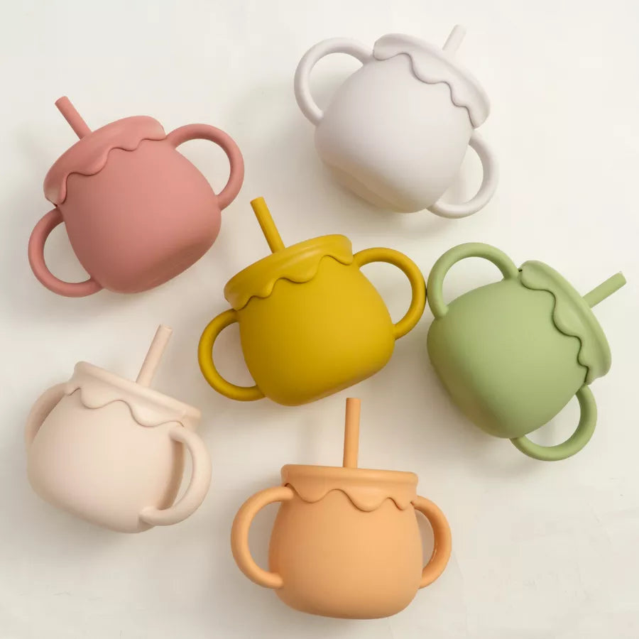 Portable silicone food cup with handle for baby on-the-go meals & toddler snacks.