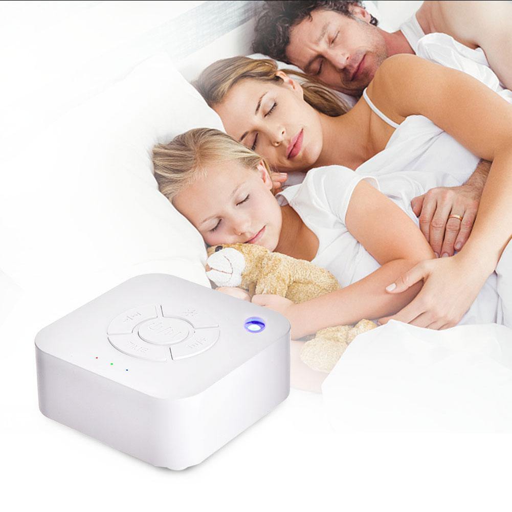 Portable white noise sound machine for baby sleep, with soft glow light, on a bedside table in a nursery.