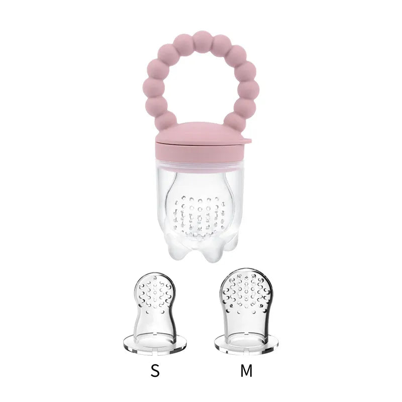 Baby gripping a yellow fruit feeder pacifier with fresh fruit pieces visible inside