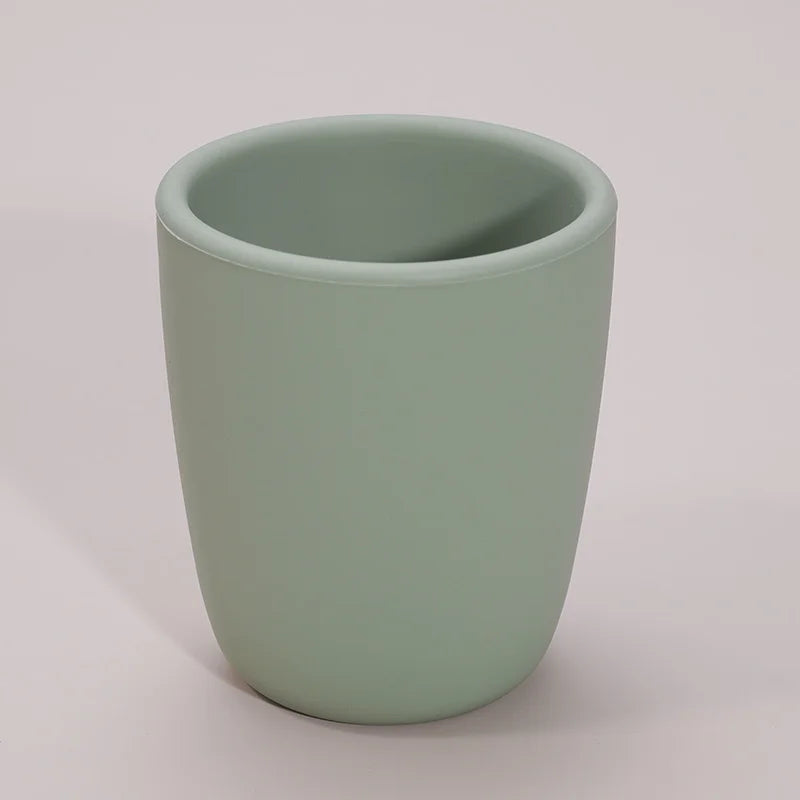 Toddler holding green silicone snack cup, demonstrating spill proof design