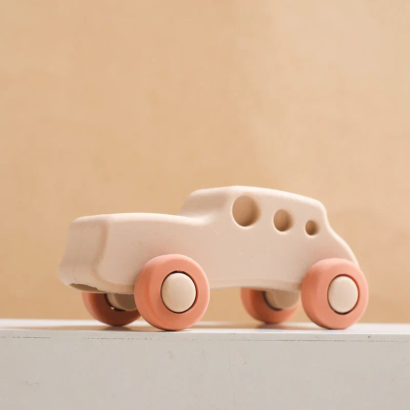 Baby chewing on a red silicone car teether, promoting healthy oral development