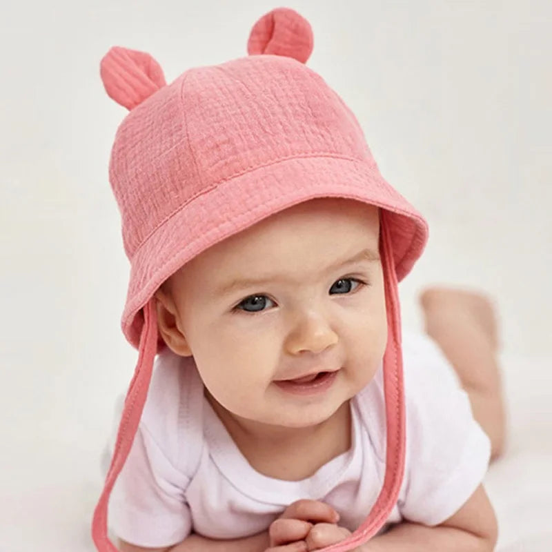 Infant sun protection bucket hat, reversible with khaki heart print, soft cotton material.