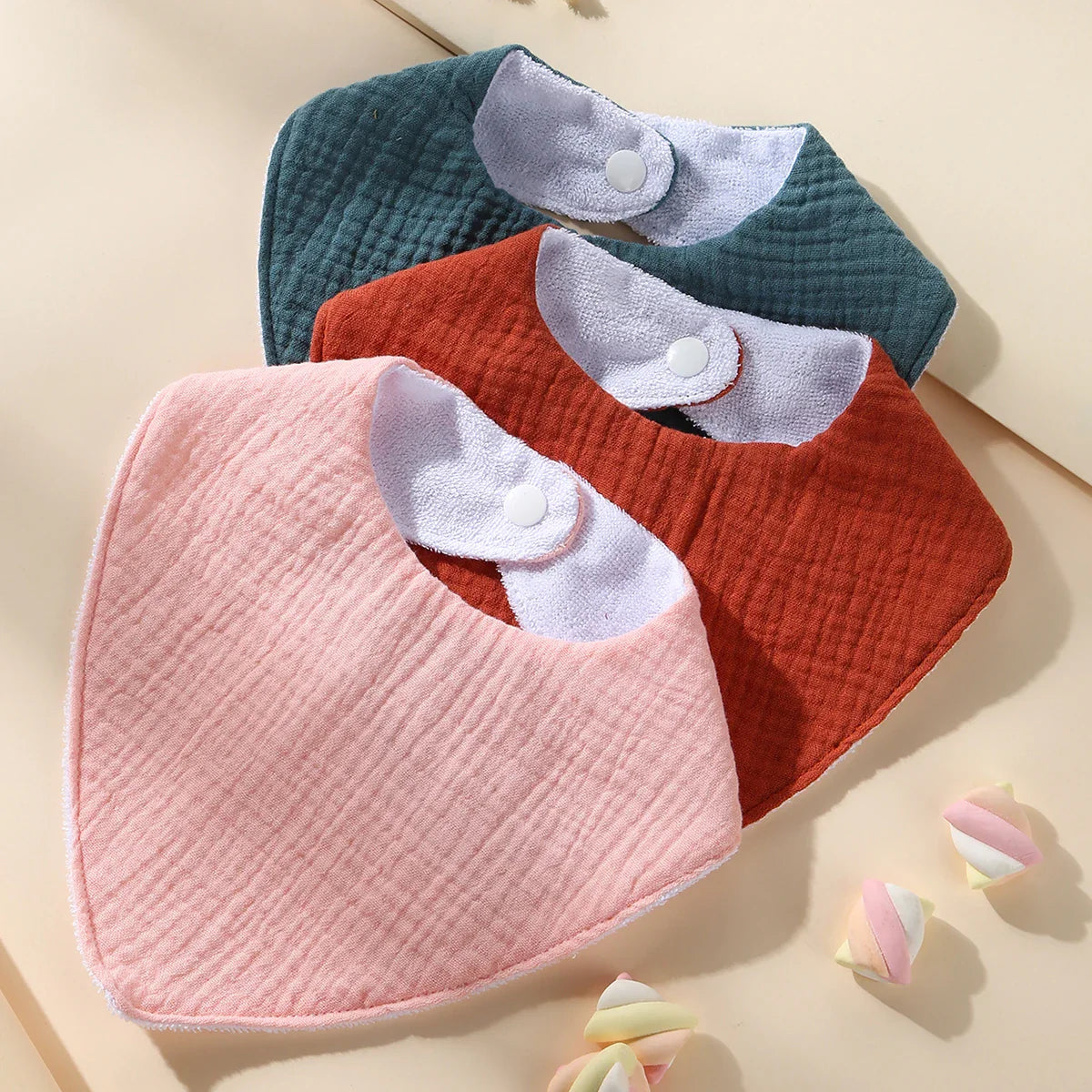 Three assorted color waterproof muslin cotton baby bibs, essential for spill protection during baby feeding.