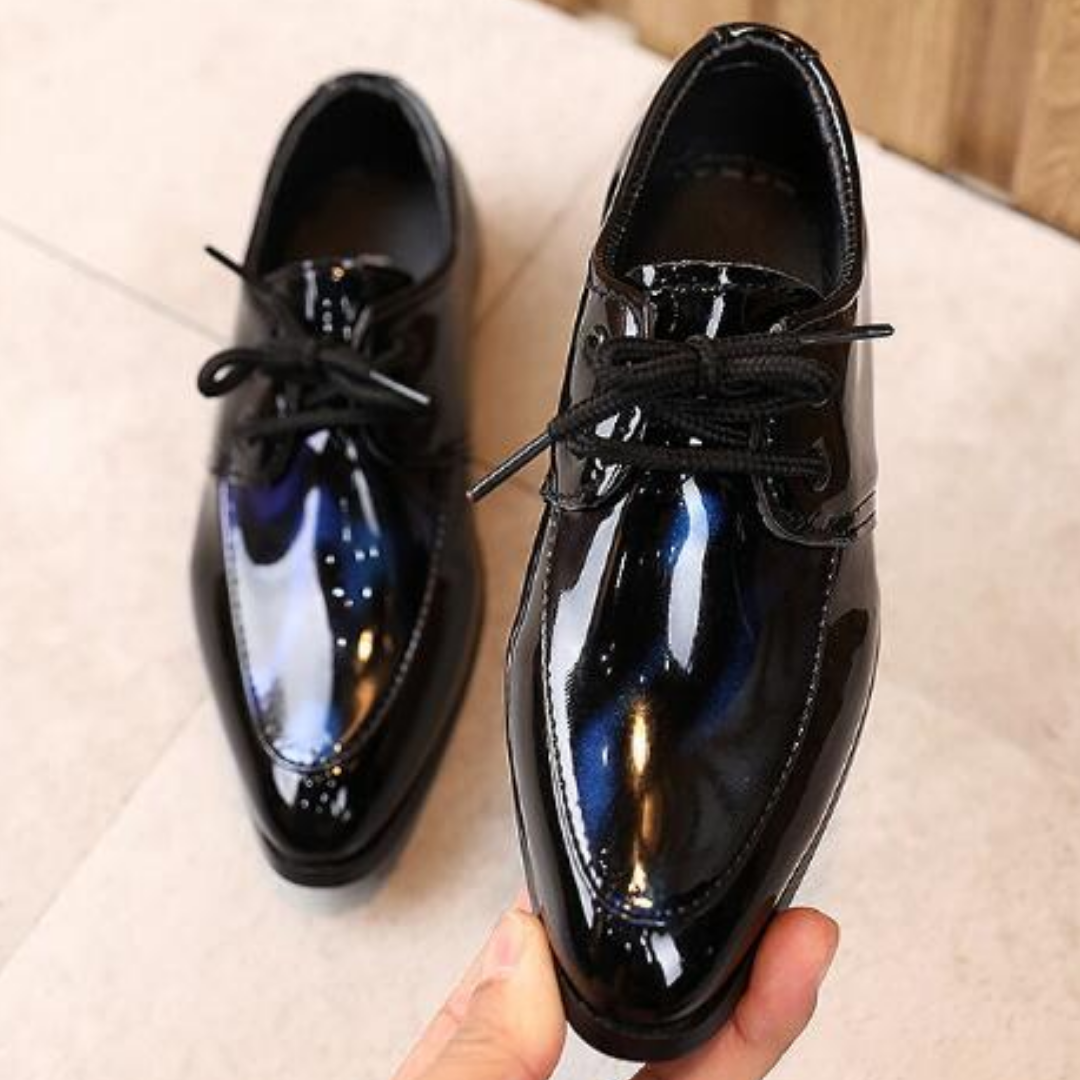 Close-up of boys' formal leather slip-on shoes with a glossy finish and pointy toe
