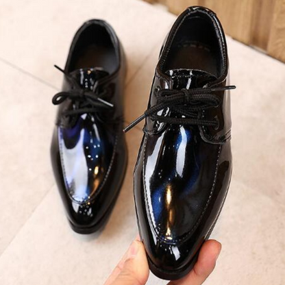 Close-up of boys' formal leather slip-on shoes with a glossy finish and pointy toe