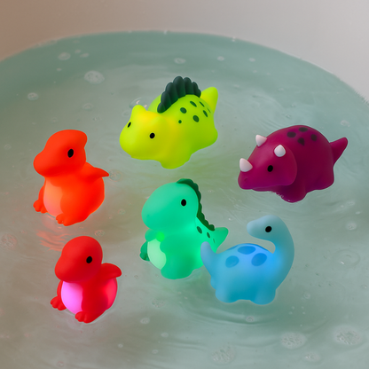 Six colorful light-up dinosaur bath toys in water, glowing playfully for kids' bath time fun