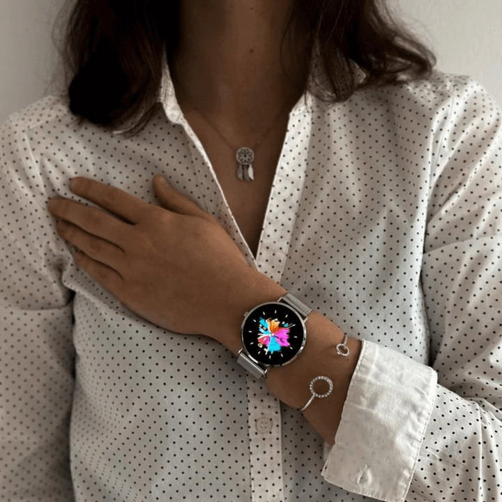 Close-up of a silver women's smartwatch display, showing heart rate and step count metrics clearly.