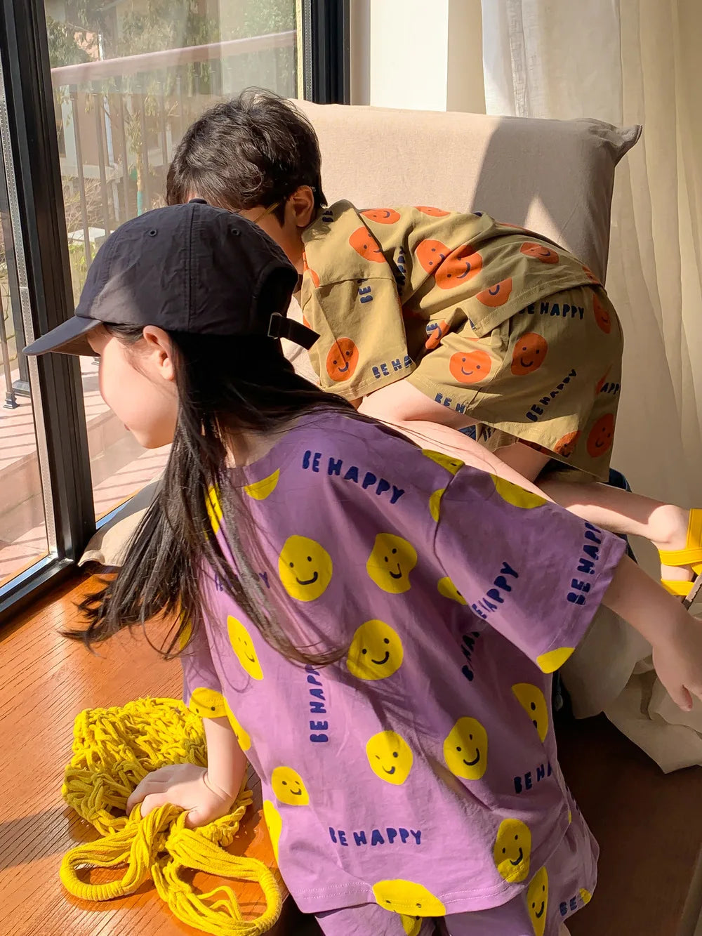 Kids' two-piece set for summer, featuring a vibrant cartoon smiley face on a blue short-sleeved top.
