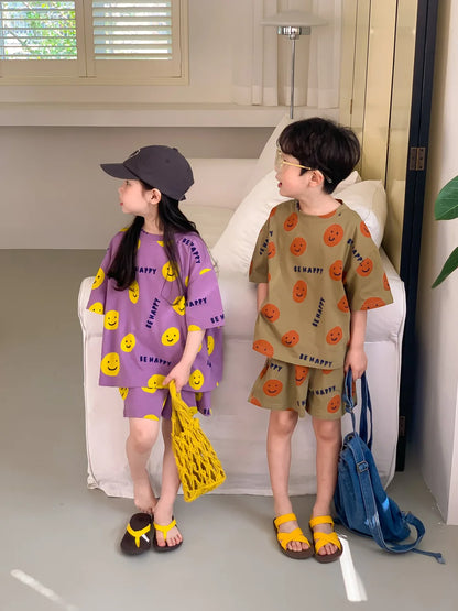 Detailed image of the fabric and playful smiley face design on this kids' short-sleeved outfit.