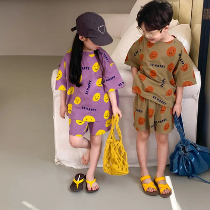 Unisex kids' two-piece set featuring a joyful cartoon smiley face on a blue short-sleeved shirt.