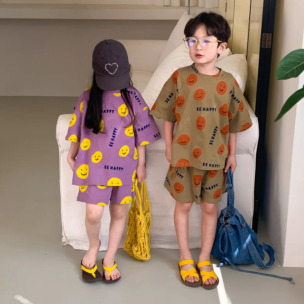 Full view of a kids' smiley face cartoon short-sleeved t-shirt and shorts set on a white background.