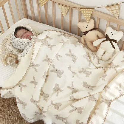 Baby peacefully sleeping in a cozy white 4-layer cotton swaddle blanket for nursery comfort