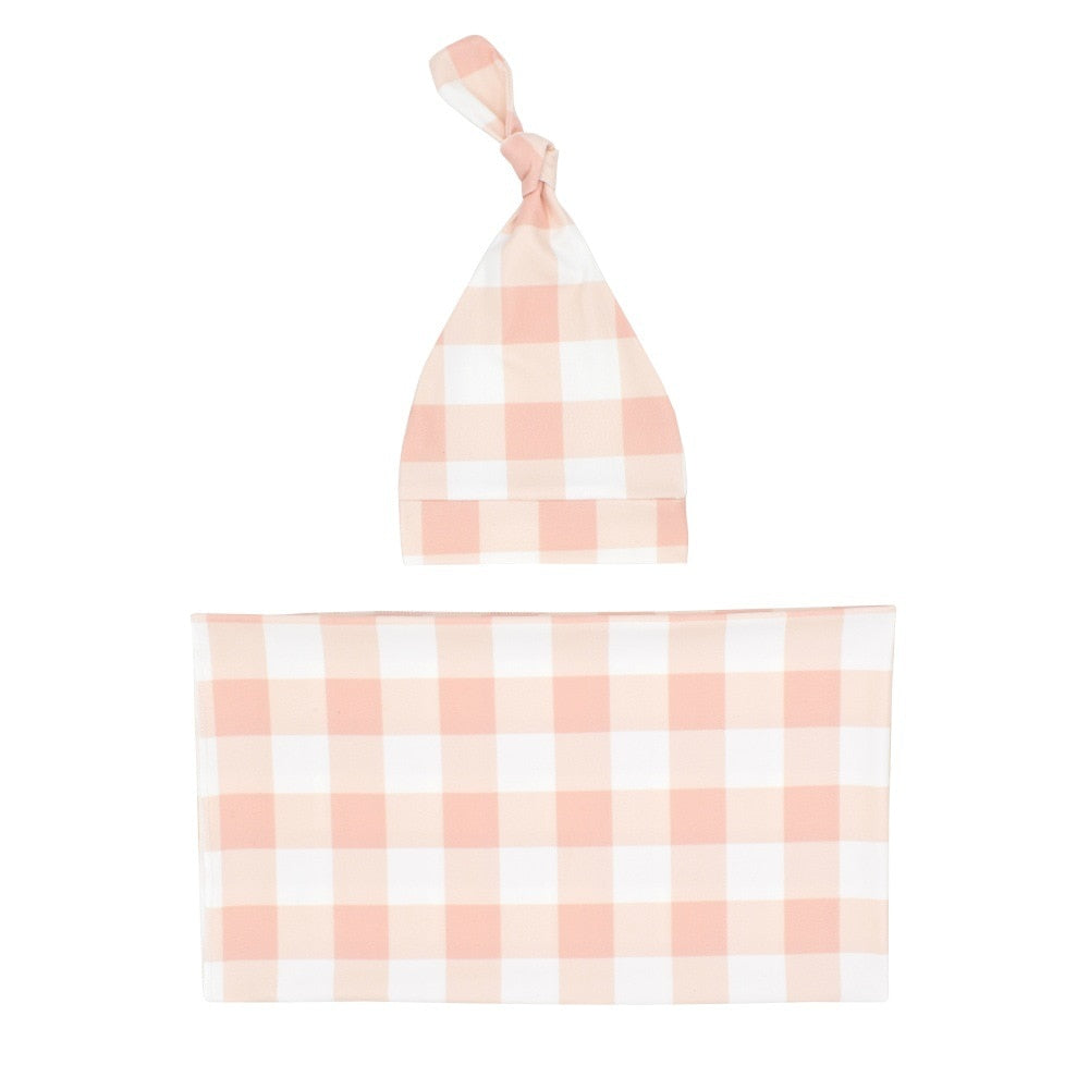 Newborn infant swaddle blanket in classic plaid pattern with coordinating baby hat, cozy comfort.
