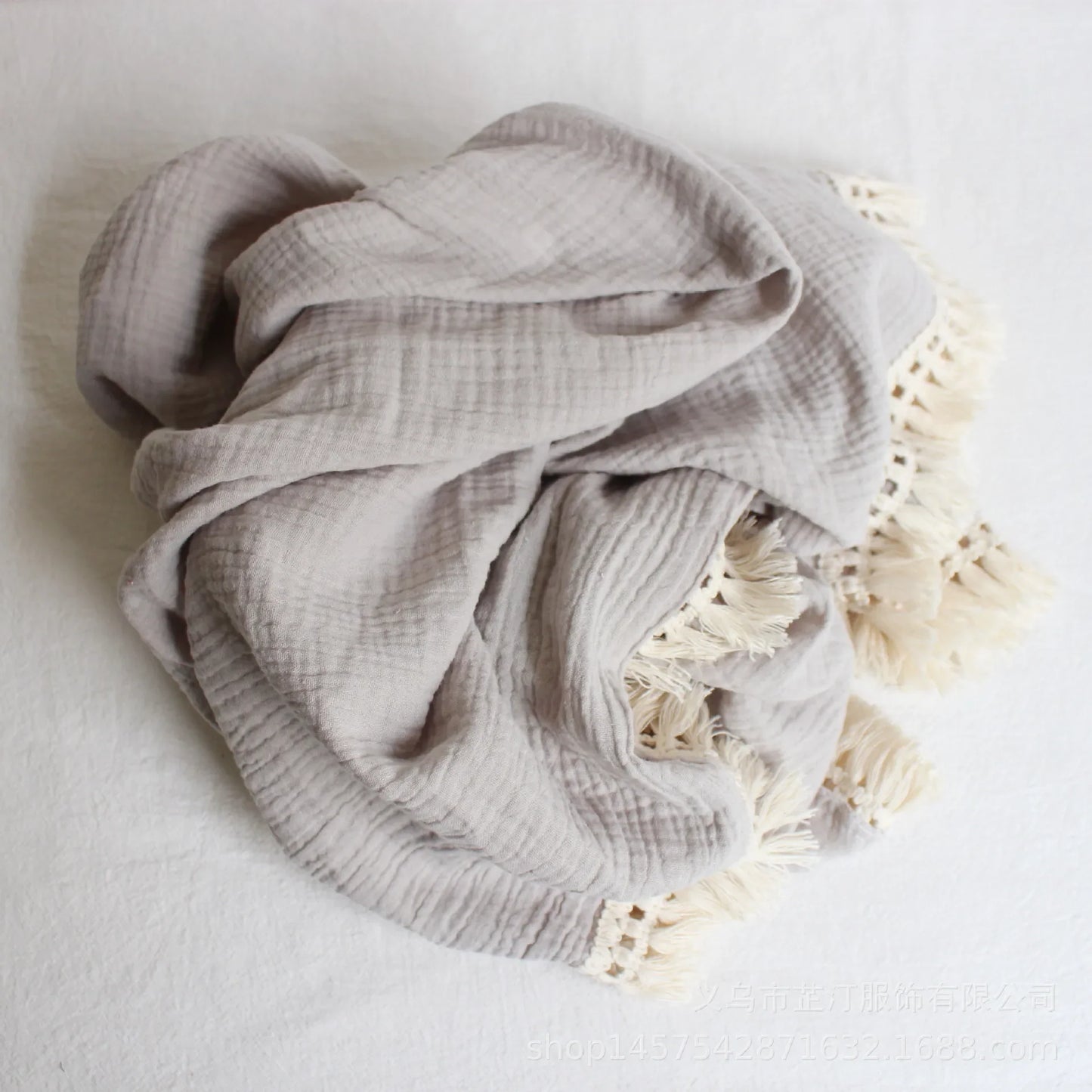 White cotton swaddle with playful tassels, essential newborn wrap for comfortable and secure swaddling