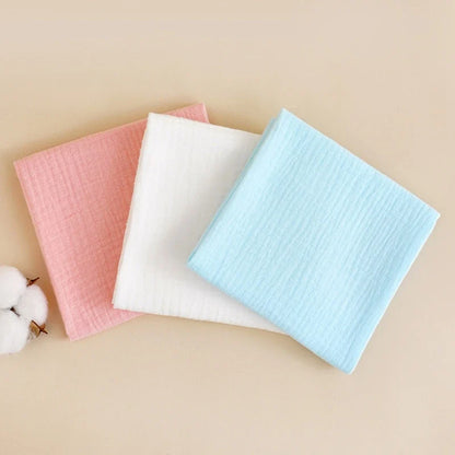 Stack of folded white reusable cotton gauze diapers, ideal for sustainable baby care