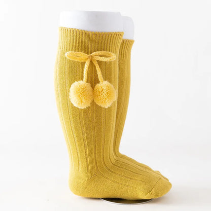 Little feet in soft knit knee-high baby socks, comfortable toddler wear.