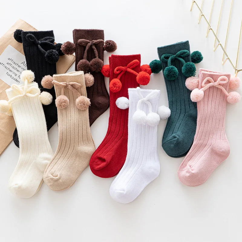 Seasonal soft knit knee-high baby socks, festive patterns for holidays.