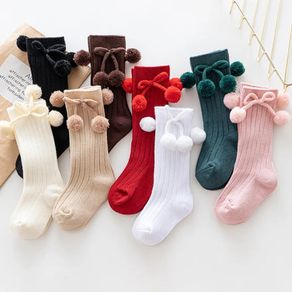 Seasonal soft knit knee-high baby socks, festive patterns for holidays.