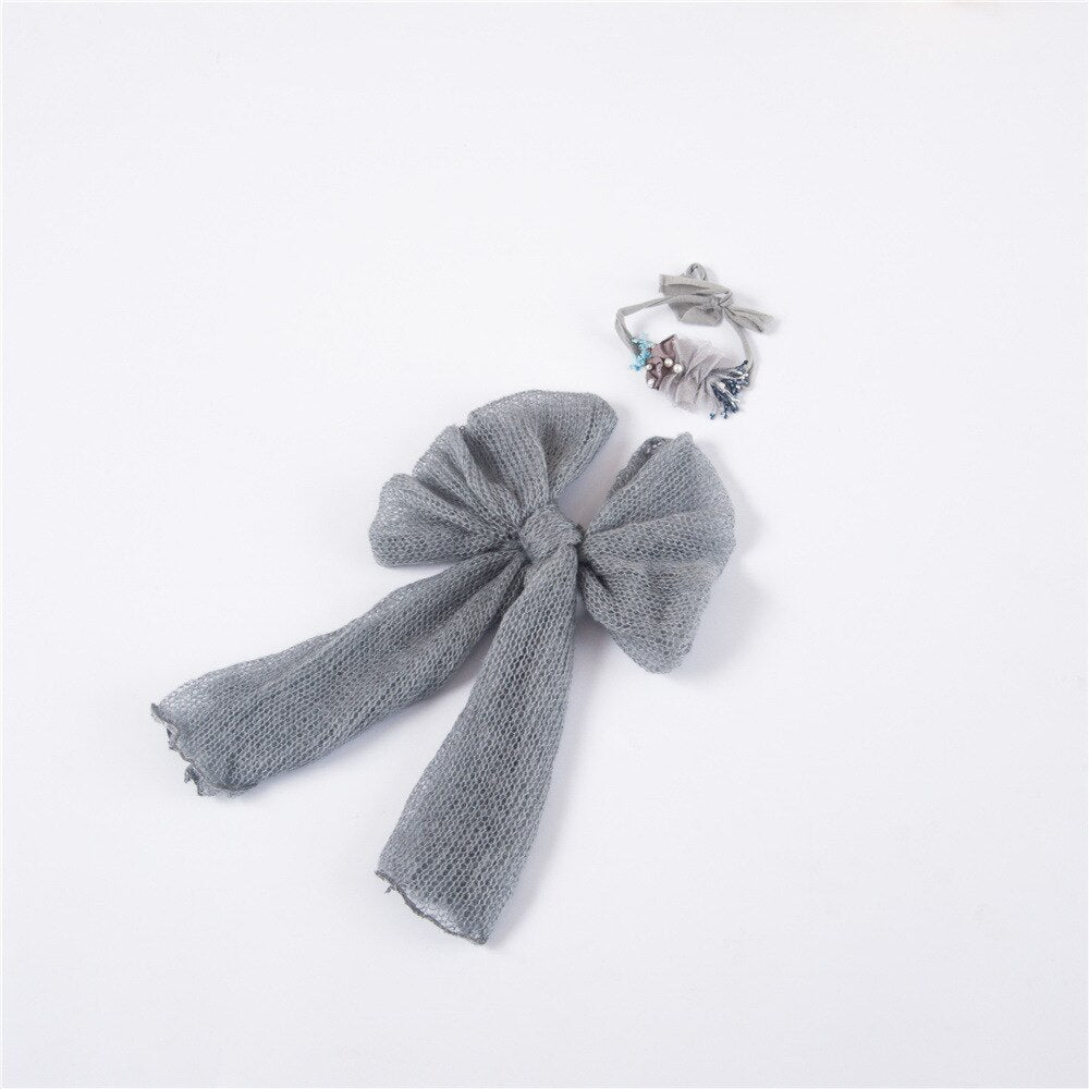Close-up of a baby wrapped in a soft, stretchy knitted blanket with a matching bow headband, photo prop.