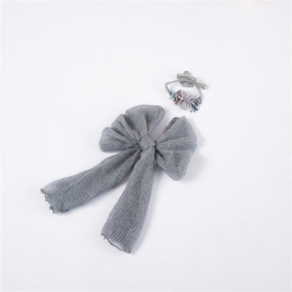 Close-up of a baby wrapped in a soft, stretchy knitted blanket with a matching bow headband, photo prop.