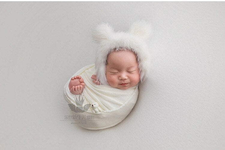 Baby photo shoot props with a soft gray swaddle blanket, matching hat, and tiny doll accessory.