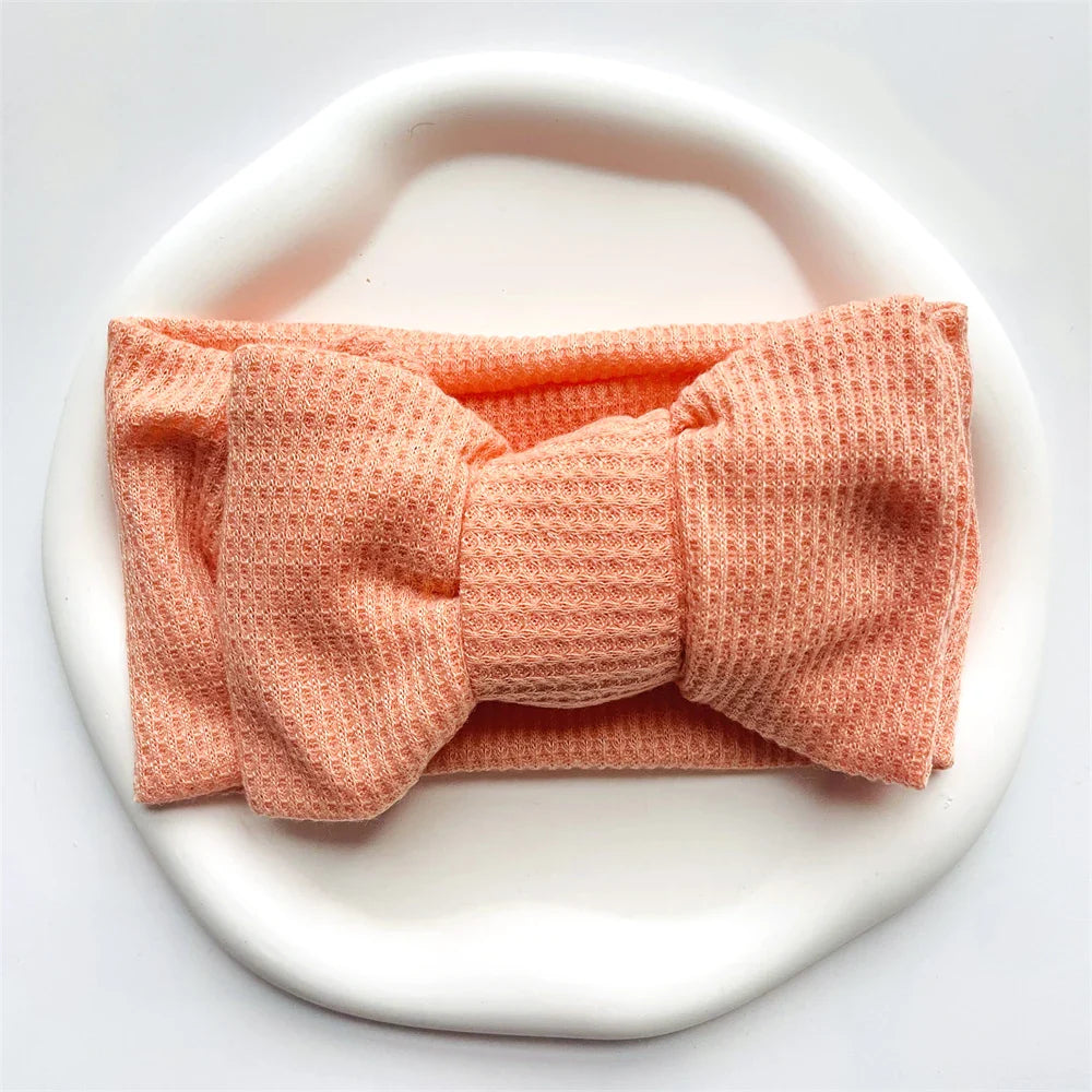 Close-up of a pink cotton baby bow headband, showing soft fabric detail