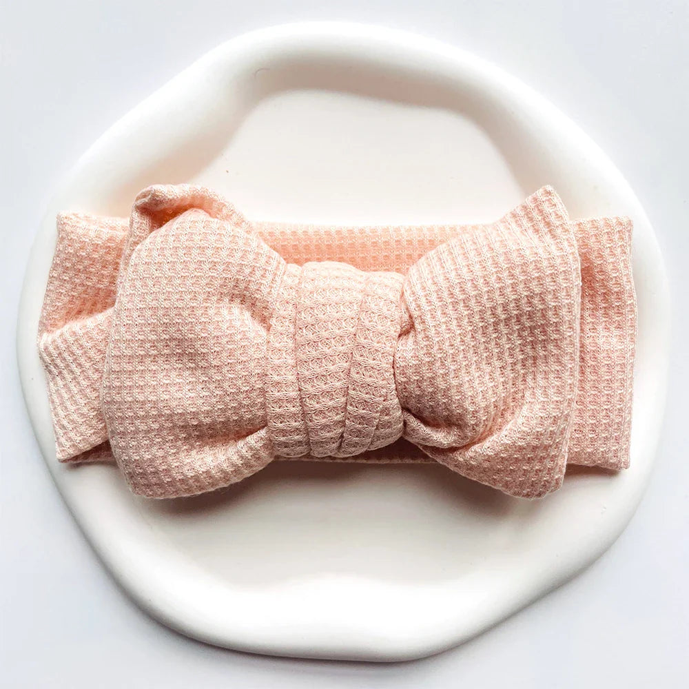 Newborn wearing an aqua soft cotton bow headband, gentle and adorable