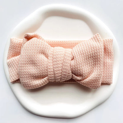 Newborn wearing an aqua soft cotton bow headband, gentle and adorable