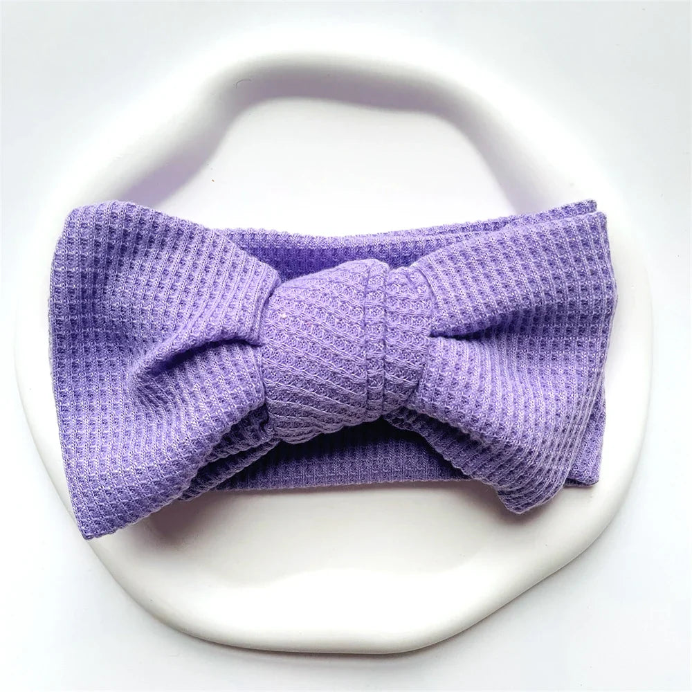 Infant girl sleeping peacefully with a lavender cotton bow headband on