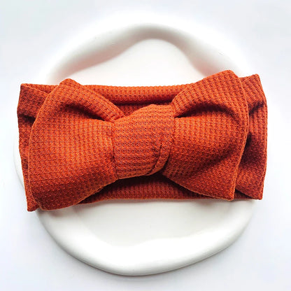 Peach soft cotton infant headband with bow, adding charm to baby fashion
