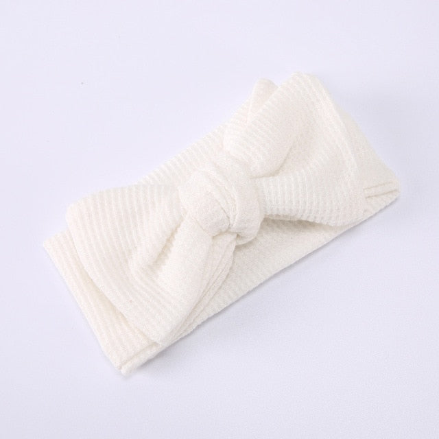 Baby girl wearing a red elastic bow headband, cute and fashionable infant