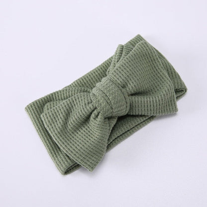 Infant modeling a yellow soft elastic bow headband, adorable baby accessory