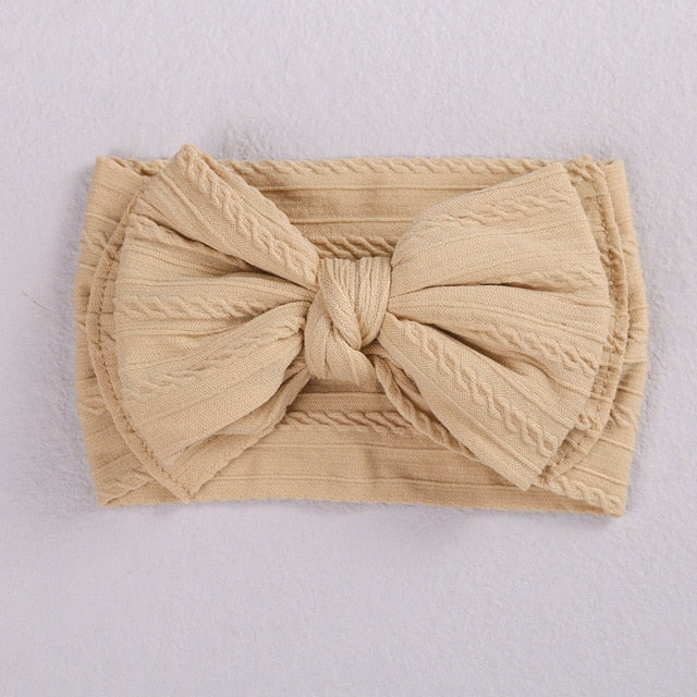 Side view of a baby's head with a blue soft elastic bow headband, cozy fit